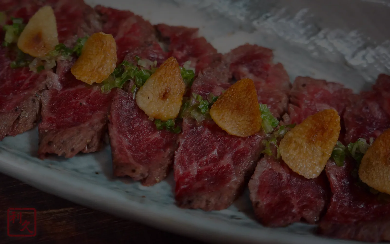 Thinly sliced seared beef topped with crisped garlic chips and scallion